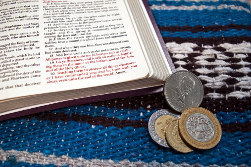 Bible open to Matthew 28:18-20 with the call to missions: Go and make disciples of all nations. Placed with a Mexican blanket and pesos.