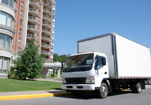 Delivery truck park in front of luxurious condominium building.