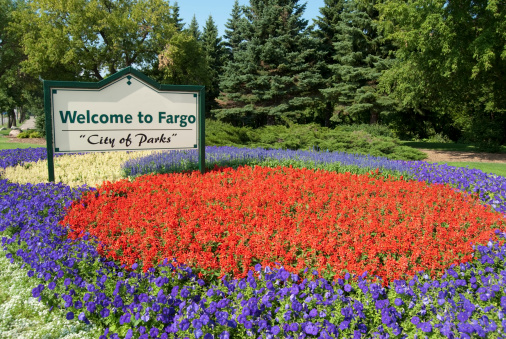 Welcome to Fargo sign in a public garden surrounded by colorful flowers.