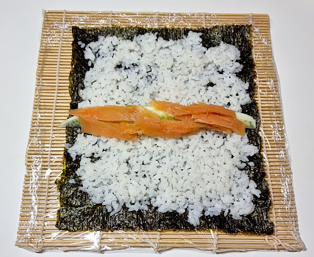 Putting rice and salmon on a nori sheet while making sushi