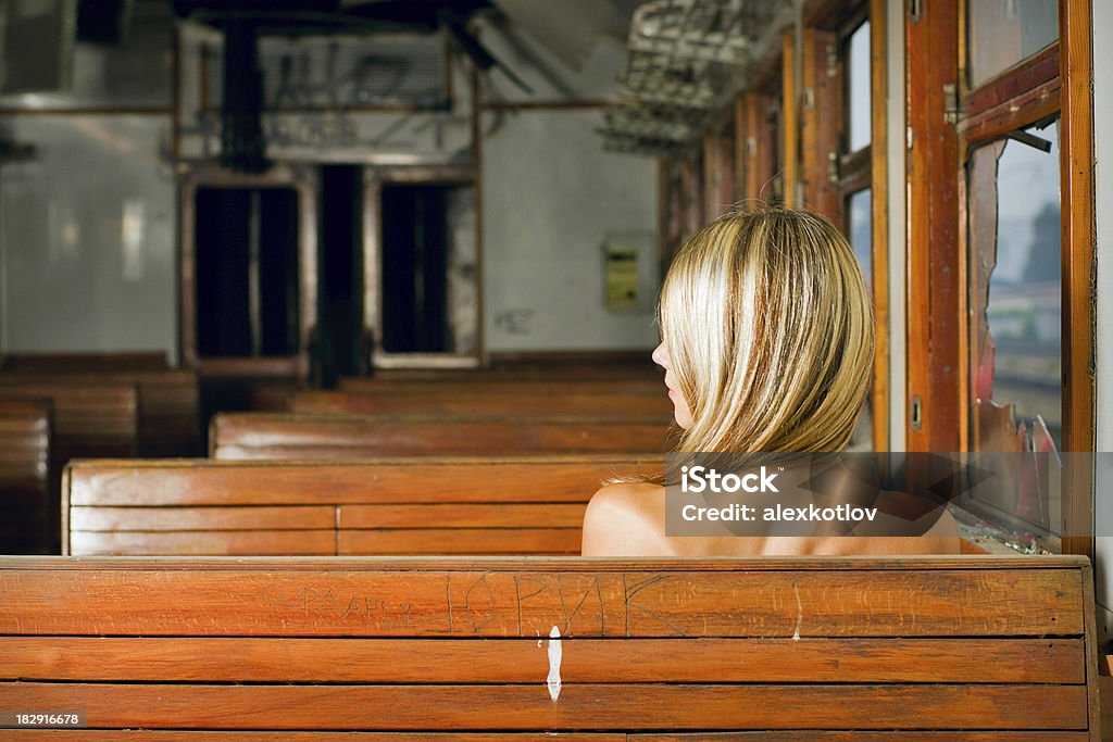 Giovane donna seduta sulla panchina in treno - Foto stock royalty-free di Persona di sesso femminile