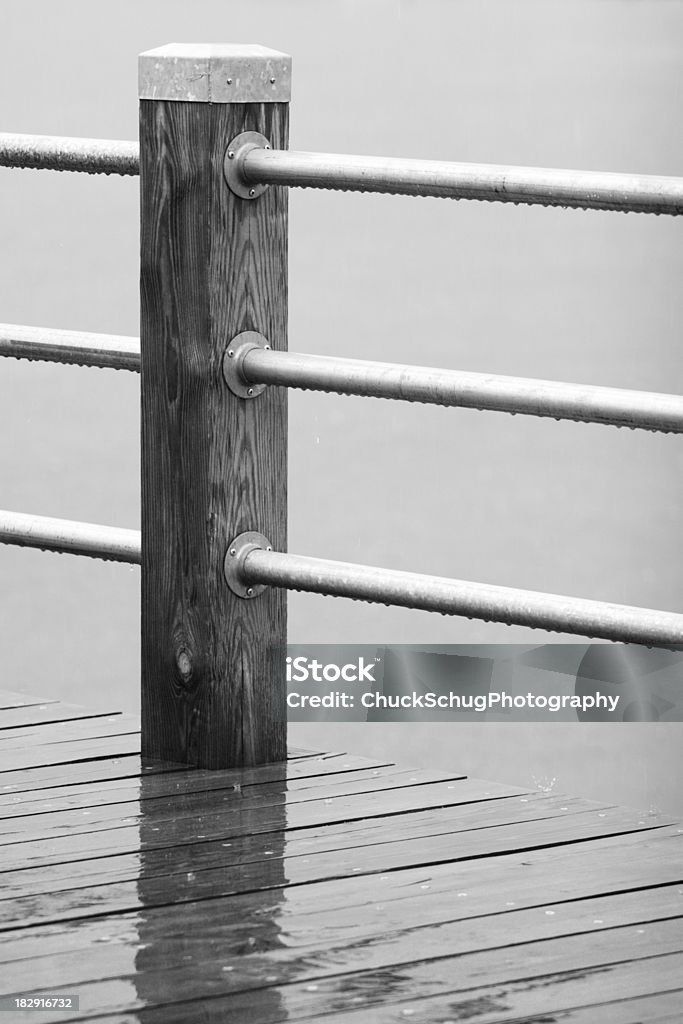 Rain Fence Post Railing Rain falls on fence post and railing with droplets splashing off the deck and hanging from the railing.  Motion blur on falling droplets.  Monochrome.  Charlotte, New York, 2007. Abstract Stock Photo