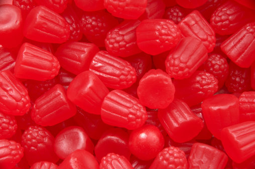 Horizontal studio shot of red gummi candy (with one round candy hiding).