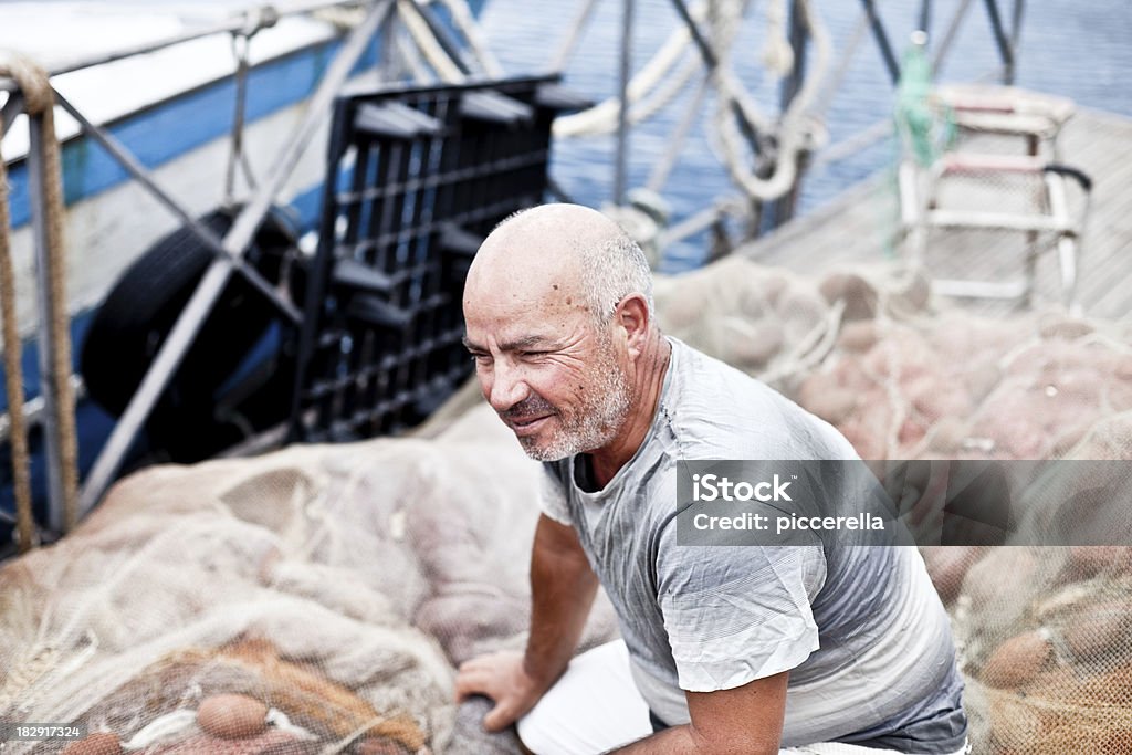 Crouched Fisherman On Fishing Net Puglia Stock Photo