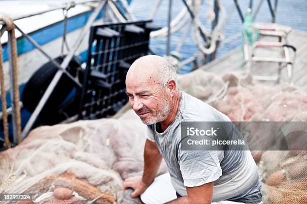 Crouched Fisherman On Fishing Net Stock Photo - Download Image Now - Puglia, Italy, 60-69 Years