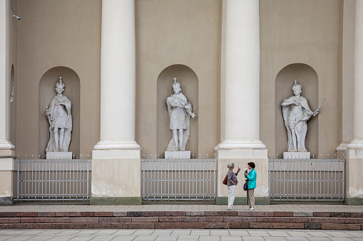 Vilnius, Lithuania - May 13, 2023: Two senior women are talking to each other in front of Cathedral Basilica of St. Stanislaus and St. Ladislaus.
