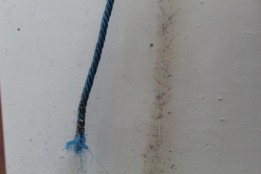 Close-up of a blue slack rope on a white wall background. suitable for copy space and background themes.
