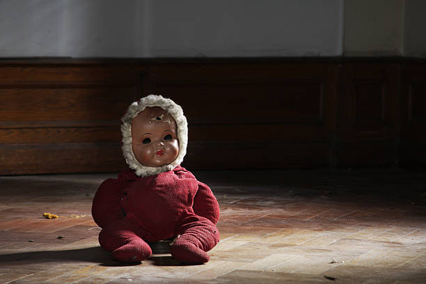 Vintage doll on parquet floor in a dark room stock photo