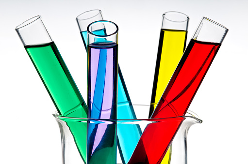 Detail of a colorful test tubes inside a beaker, over a white background.