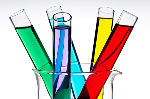 Close up of colorful liquids in test tubes and glass laboratory flasks on a pink yellow gradient background. Empty podium for product display with laboratory space.