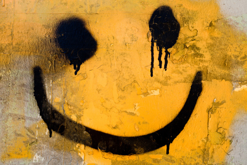 Spray-painted graffiti smiley face on a wall.
