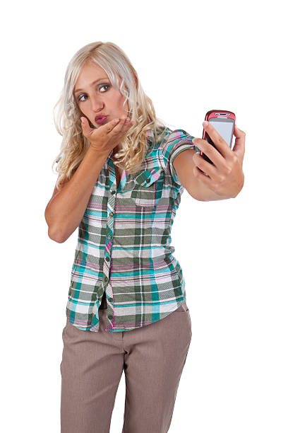 Cute Teen Girl Taking Self-Portrait On Cell Phone A cute 16 year old girl blowing a kiss as she takes a self-portrait on her cell phone. late teens isolated on white one person cute stock pictures, royalty-free photos & images