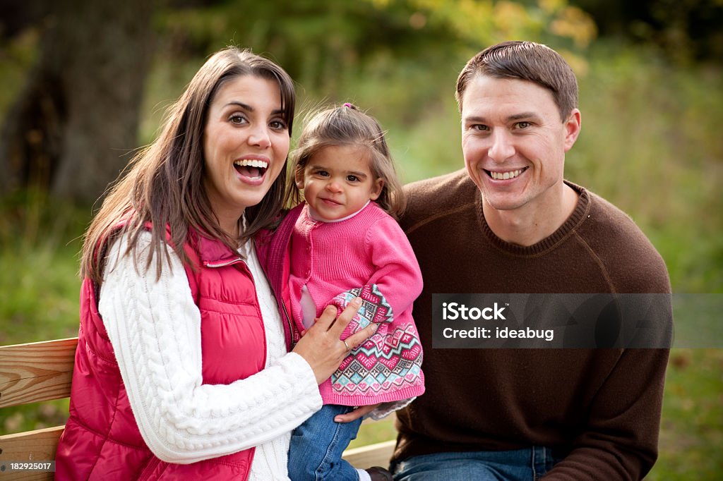 Familia feliz sentado en el banco en el Bosque en otoño - Foto de stock de Adulto libre de derechos