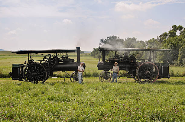 Steam Engine Farmers "Two Running Steam farmers standing next to running steam engines, holding pitch forks. Taken in Rural Illinois. (Some grain due to large amount of steam in the air)" antique pitchfork stock pictures, royalty-free photos & images