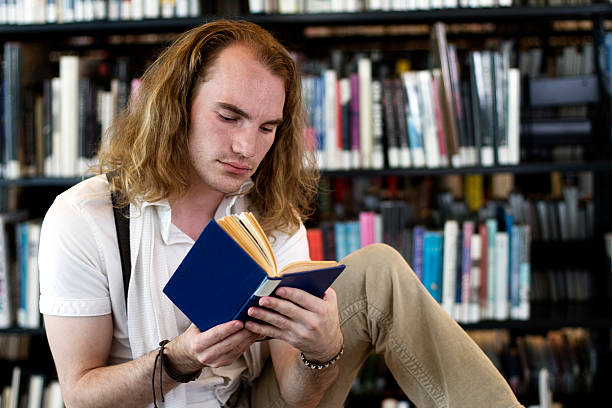 istock Young Man Reading a Book at the Library 182925872