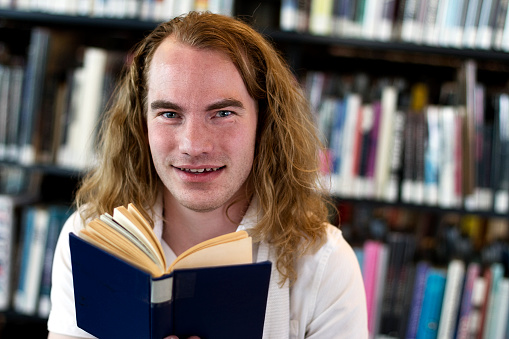 Young man reading a book at a public library.