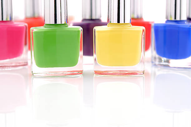 Side view of one red bottle of nail polish with reflections on mirrored surface against dark background.