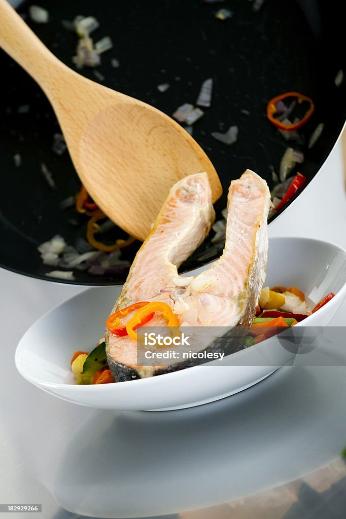 Cooked Salmon A cooked salmon steak being placed in a dish. Arranging Stock Photo