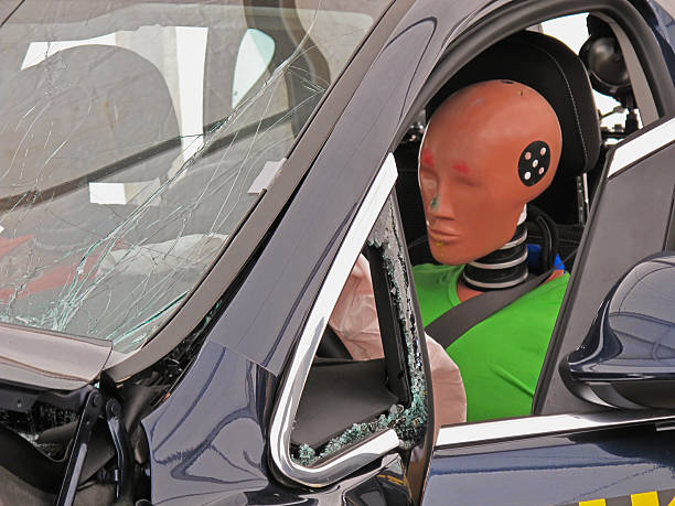 Driver's side view of a car with a crash dummy at the wheel Detail of a simulated car accident. crash test dummy stock pictures, royalty-free photos & images