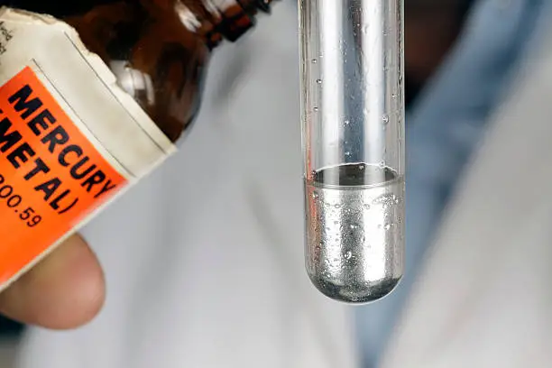 Pouring out mercury from a bottle to a test tube.