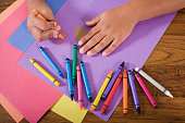Close up hands of child drawing with colorful crayons