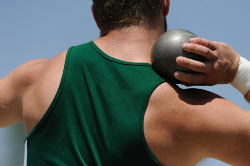 Male holding a shot put before throwing it.