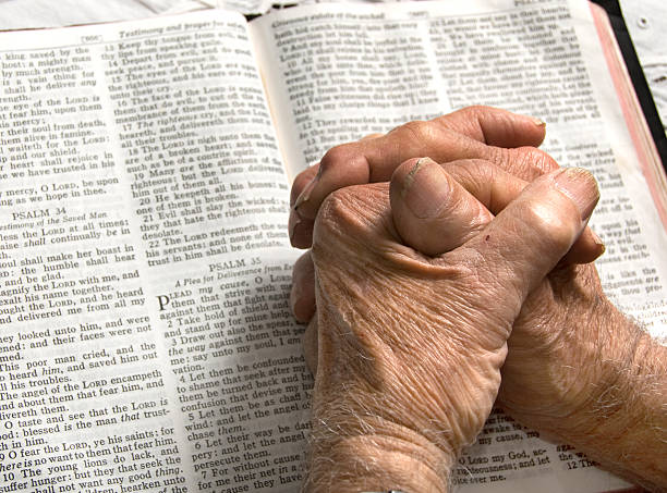 Praying Hands on a Bible An old man's hands are folded in prayer on a Bible bible verses about prayer stock pictures, royalty-free photos & images
