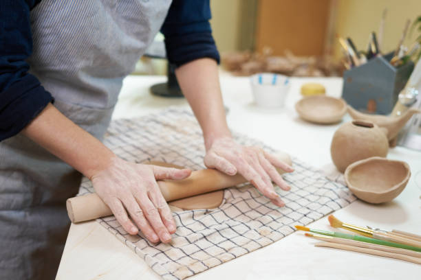 istock Hobbies concept - A woman ceramist rolls clay with a rolling pin in a pottery workshop 1829337858