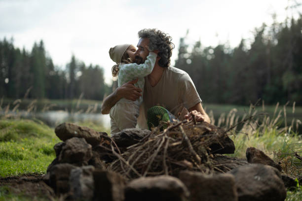 istock Dad and kid preparing campfire. Family camping at lake. copy space 1829353411