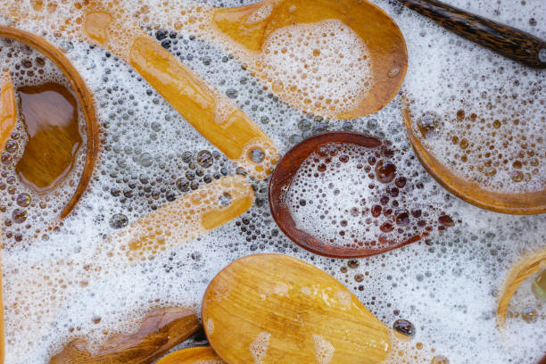 istock Wooden kitchenware in water and bubbles of dishwashing liquid 1829367932