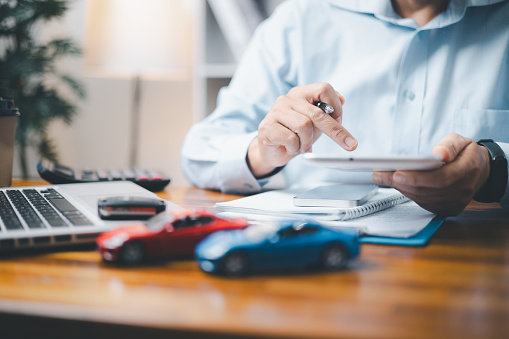 Toy Car In Front Of Businessman Calculating Loan. Saving money for car concept, trade car for cash concept, finance concept.
