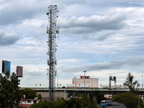 Cellular tower in residential district, in the south of Mexico City, with elevated road in the background