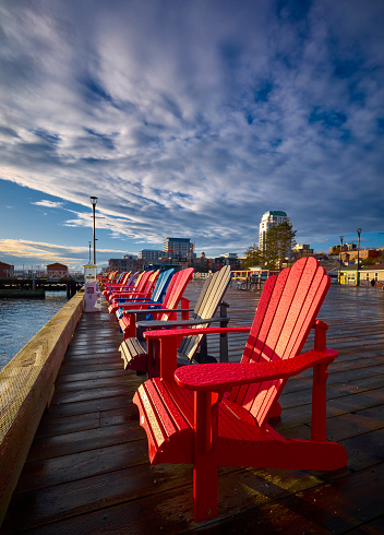Colorful chairs on harbor boardwalk on the ocean with big blue sky