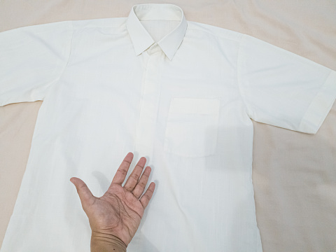 Men's white shirt on a beige background. Top view.