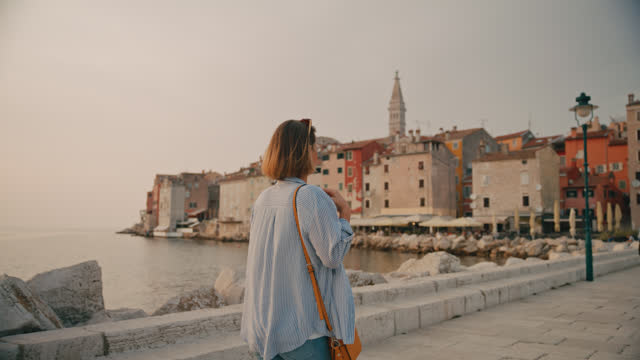 SLO MO Rear view of female tourist exploring old town in Rovinj while walking on pier by sea in Croatia
