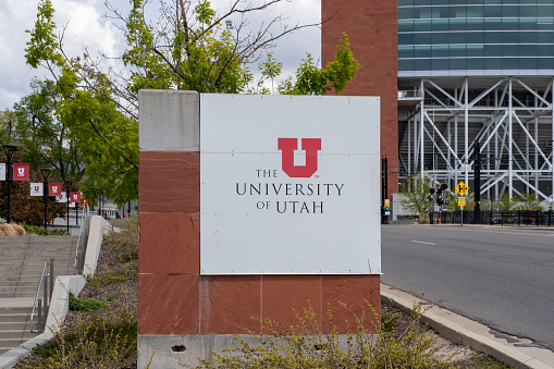 University of Utah sign with Rice-Eccles Stadium in the background in Salt Lake City, Utah, USA - May 12, 2023. The University of Utah is a public research university.