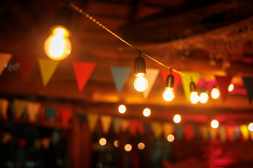 A dimly lit bar decorated with colorful flags and string lights
