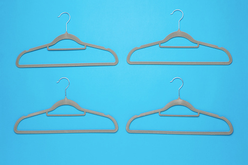 A set of four grey clothes hangers on a blue background. An accessory for storing clothes.