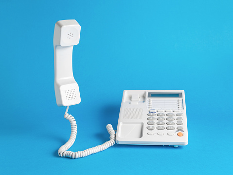 A classic white telephone on a blue background. Classic retro telephone connection.