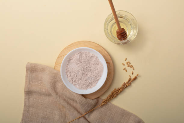 istock Rice bran powder is displayed on a ceramic plate on a wooden platform. A honey drizzle is placed in a glass of water. Rice bran powder is very effective in tightening pores and removing dirt. 1829563489