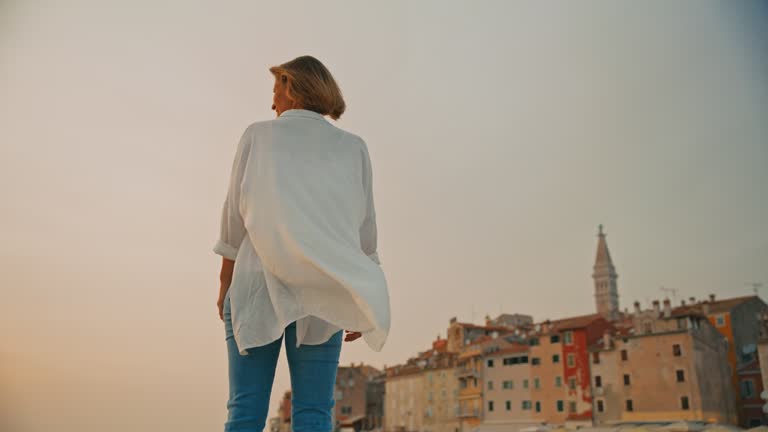 SLO MO Tilt down shot of female tourist standing against old town and clear sky at Rovinj,Croatia