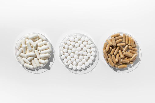 Various vitamins and dietary supplements in small medical plates on a white background. The concept of medicine, medicines.