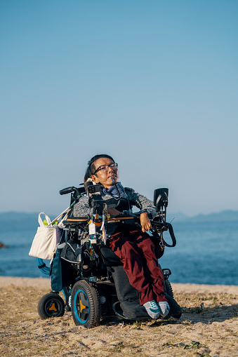 Portrait of a man in a motorized wheelchair on the beach in Japan