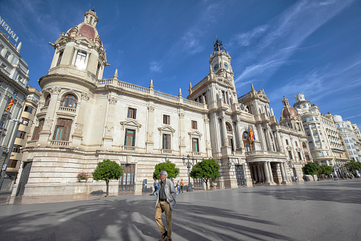 Street view of Plaza del Ayuntamiento or City Hall Plaza , Valencia, Spain. A Senior man walking by the City Hall.