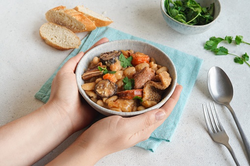 Female hands holding a bowl with Tripe stew