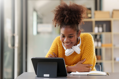 Happy young woman having video call via tablet.