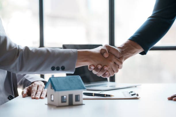 Real estate agent shakes hands with a client to sign a home purchase contract congratulating the client on the purchase. stock photo
