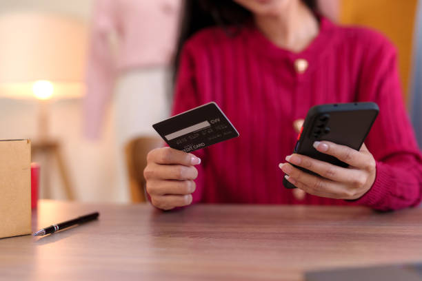 Young business woman is using smartphone for online shopping and using credit card for payment through banking application for online shopping. Young business woman is using smartphone for online shopping and using credit card for payment through banking application for online shopping. canadian coin stock pictures, royalty-free photos & images