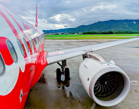 Chiang Mai - Thailand. October 8, 2023: AirAsia airline arriving at Chiang Mai International Airport with a backdrop of mountains and clouds. Travel and transportation concept