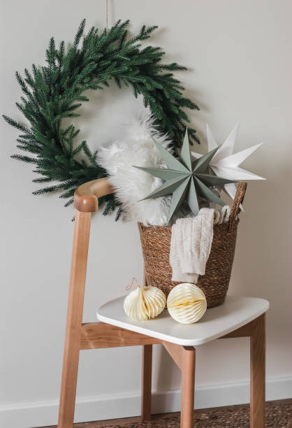 istock Christmas decor in the interior. Christmas tree wreath on the wall, basket with blankets, Scandinavian stars on a chair 1829731342